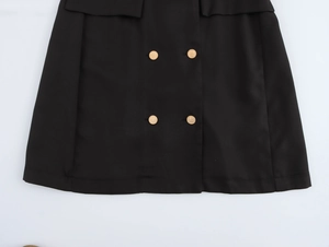 Detail of black mini dress hem featuring four decorative gold double-breasted buttons