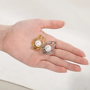 Detail of irregular hammer textured 18k gold and silver earrings with large pearls in palm