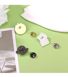 Detail view of cute cartoon metal pins with butterfly clasps and rubber backings