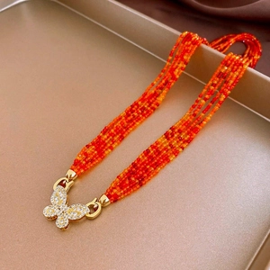 Detail of layered orange ceramic beads with a sparkling gold butterfly clasp