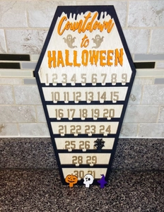 Macro view of wooden coffin-shaped Halloween countdown calendar with spider and pumpkin markers