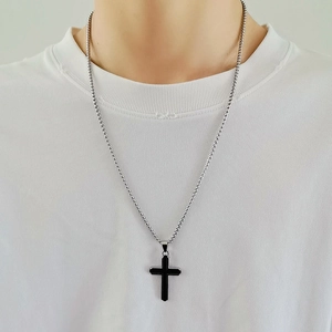 Chaîne à billes argentée avec pendentif croix noire minimaliste portée par un mannequin