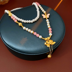 Close-up of new Chinese style pearl necklace with gold lotus and butterfly pendant detail