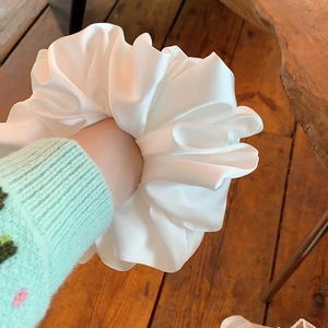 Oversized white pleated satin hair scrunchie shown on wrist for a stylish look