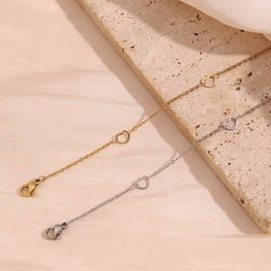 Close-up of gold and silver heart-shaped link chains on elegant beige travertine background