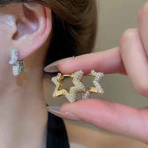Close-up of gold star earrings with pavé-set white cubic zirconia and a lever-back closure