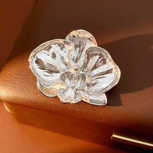 Macro detail of orchid flower brooch in silver metal on a brown leather jewelry box