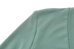 Close-up of sage green ribbed knit fabric texture on a slim fit sports jumpsuit