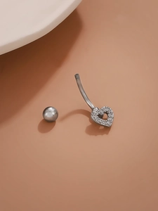 Macro detail of silver heart navel ring with crystal pavé and screw-off ball top