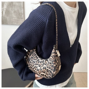 Detail of trendy leopard print crescent bag with sleek black piping and metal hardware