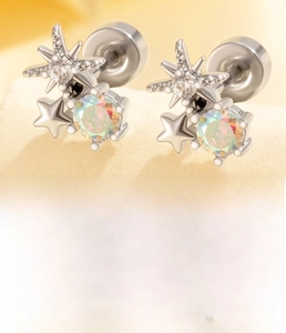Close-up of star-shaped titanium steel ear studs with colorful zircon stones and specs