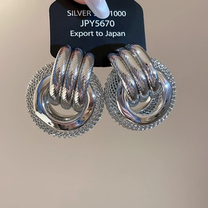Détail des boucles d'oreilles créoles argentées avec texture en maille métallique
