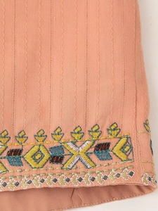 Close-up of pink-orange cotton fabric with colorful geometric floral embroidery details