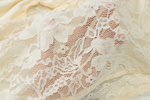 Detailed macro view of white floral lace fabric with intricate embroidery and mesh texture