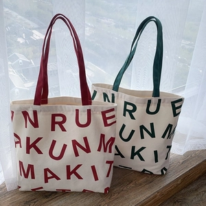 Detail of red and green canvas tote bags with large lettering on a wooden windowsill
