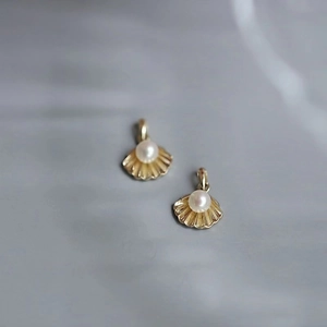 Detail of elegant gold-plated shell pendant with white pearl inlay on soft gray background