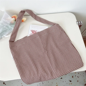 Detailed close-up of large houndstooth tote bag on table with book and flowers