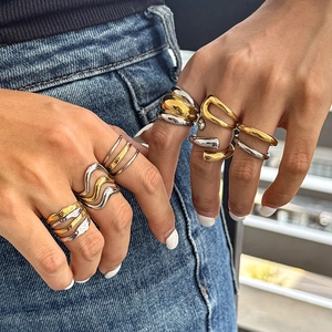 Detail of stacked two-tone wavy stainless steel rings on denim background