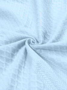 Macro shot of light blue jacquard fabric showing spiral texture and woven details of the shirt