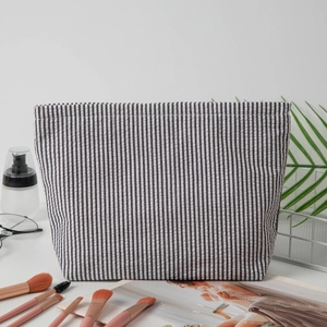 Macro shot of striped seersucker makeup bag with brushes and cosmetics in a lifestyle setting