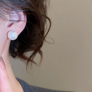 Close-up of a high-luster white pearl earring on an ear for a classic vintage look
