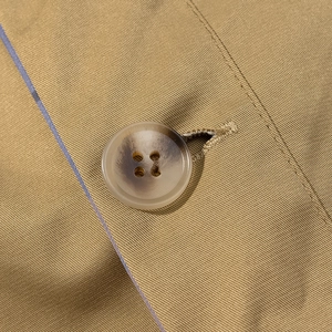 Close-up of marble pattern four-hole button on khaki twill fabric of jacket