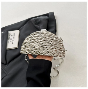 Detail of silver evening clutch bag featuring hammered texture and metal chain strap