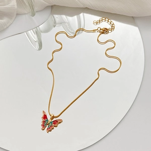 Rainbow butterfly necklace with golden snake chain and colorful enamel pendant on a mirror
