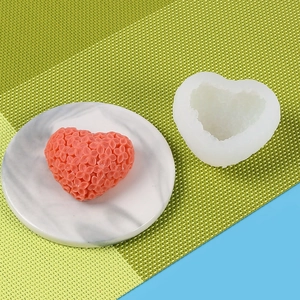 Macro shot of 3D heart flower silicone mold and pink floral scented candle on a tray