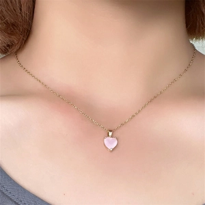 Close-up of a pink heart-shaped gemstone necklace with gold chain worn by a model