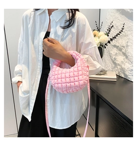 Detail of pink quilted puff bag showing soft fabric texture and pleated handle