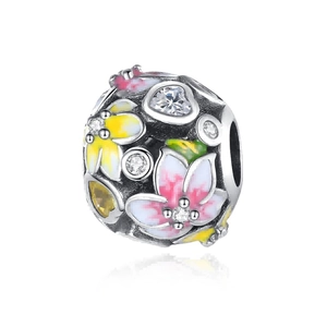 Macro detail of a silver floral bead with pink yellow enamel and sparkling zircons