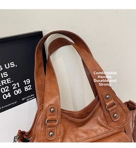 Close-up of brown vintage leather tote bag showing handle detail and silver metal rivets
