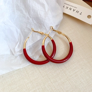 Macro shot of large red and gold hoop earrings on a textured artistic background