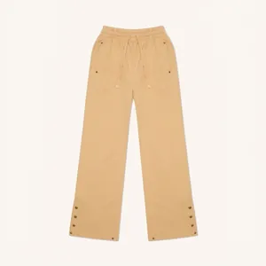 Detail view of khaki wide-leg track pants with side metal snap buttons and drawstring waist