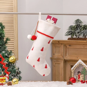 White plush Christmas stocking with red tree embroidery and festive hanging pom-poms
