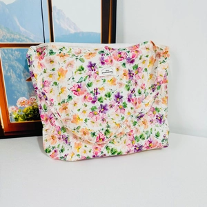 Close-up of floral canvas shoulder bag with pink blossom print and brand label