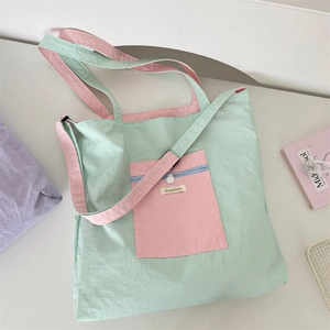 Detailed view of mint green and pink nylon tote bag with brand label and front pocket