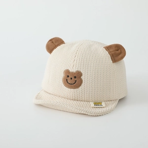 Détail de la casquette bébé en velours côtelé beige avec oreilles d'ours et broderie ours