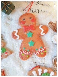Gingerbread man ornament with festive red and green accents on snowy background