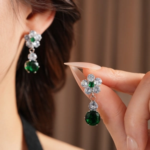Detail of flower-shaped silver necklace and earrings with green cubic zirconia crystals