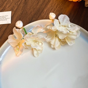 Detail of white fabric floral earrings with rosebuds and crystal water drop pendants