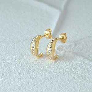 Macro shot of gold-plated 925 sterling silver C-shaped earrings with zircon inlay