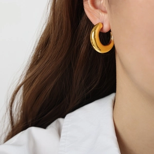 Minimalist thick gold-plated C-shaped stainless steel hoop earrings worn by a model