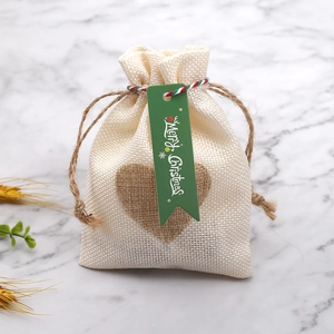 Dettaglio del sacchetto regalo in iuta con motivo a cuore e etichetta verde Merry Christmas