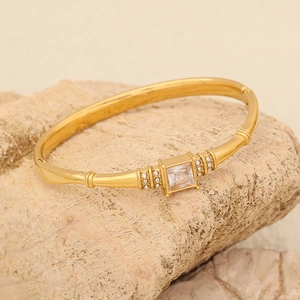 Dettaglio del bracciale in acciaio dorato con gemma quadrata su pietra naturale