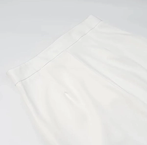 Détail du pantalon blanc à taille haute avec ceinture ajustée et pinces élégantes
