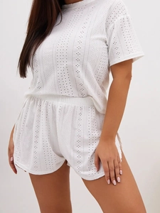 Detail of white two-piece pajama set featuring delicate eyelet embroidery texture