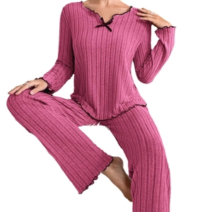 Women's pink ribbed loungewear set with black lettuce trim and bow on white background