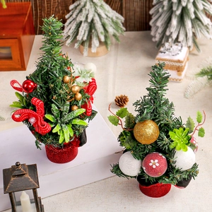 Miniature pine needle Christmas trees with red berries and golden ornaments on a wood base